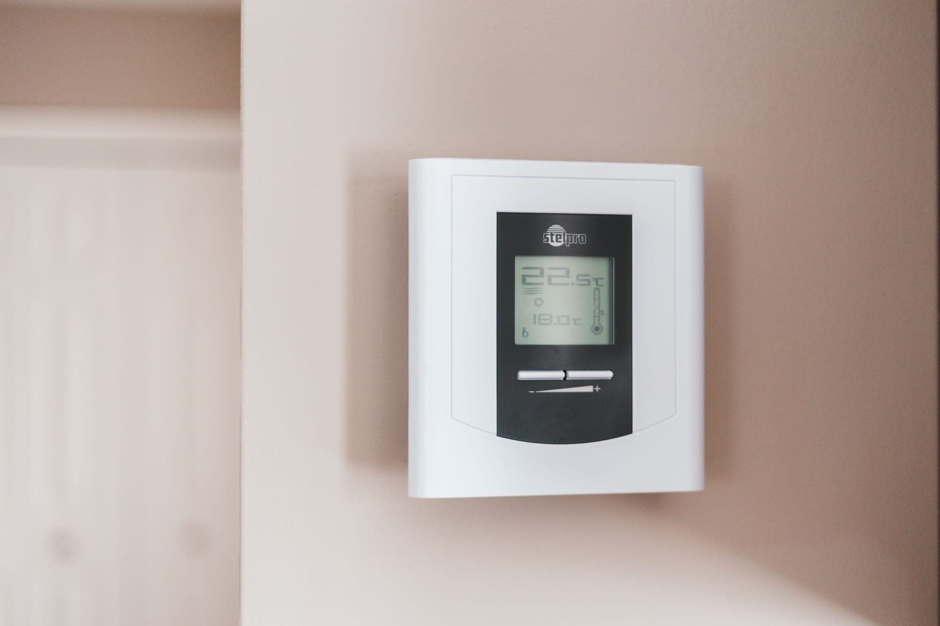 A wall-mounted digital thermostat, illustrating the temperature-control class